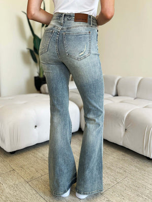 Model wearing high waist flare Judy Blue jeans showcasing back view and flare leg silhouette in stylish indoor setting.