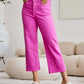 Woman wearing RFM Jeans' Crop Chloe Full Size Tummy Control High Waist Raw Hem Jeans in pink, paired with heels.