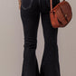 Rear view of woman wearing Bella Road Button-Fly Flare Jeans with Pockets in black, paired with a brown leather crossbody bag