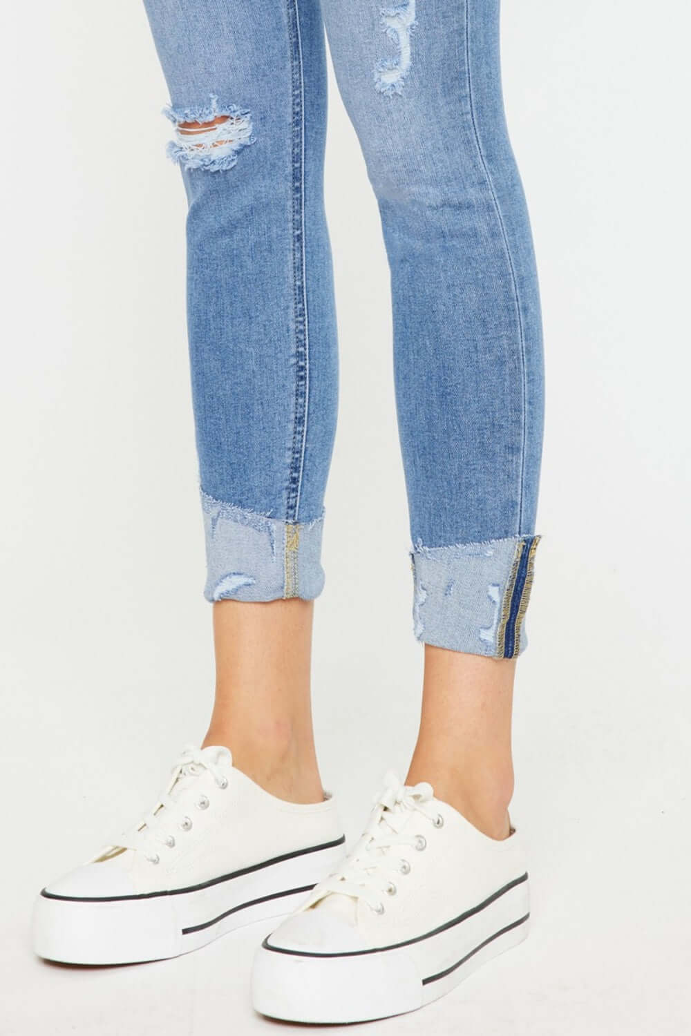 Distressed Cat's Whiskers Button Fly Jeans with rolled cuffs and white platform sneakers for a trendy casual look