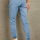 Back view of Baeful Distressed Denim Pocketed Joggers in light blue, featuring pockets and fringe, worn with white ankle boots.