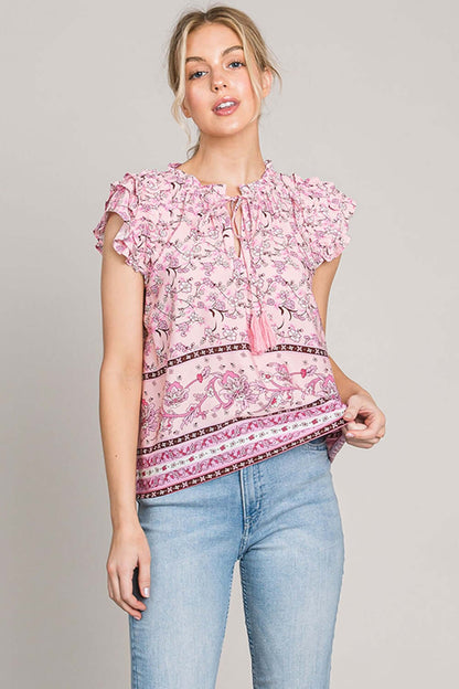 Woman wearing a pink print ruffle sleeve detail blouse with blue jeans for a chic and feminine look.