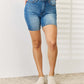 Woman wearing Tummy Control Double Button Bermuda Denim Shorts by Judy Blue Jeans, showcasing stylish and comfy full-size shorts.