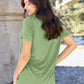 Woman wearing Basic Bae Bamboo V-Neck Short Sleeve T-Shirt in green, standing outdoors with her back turned