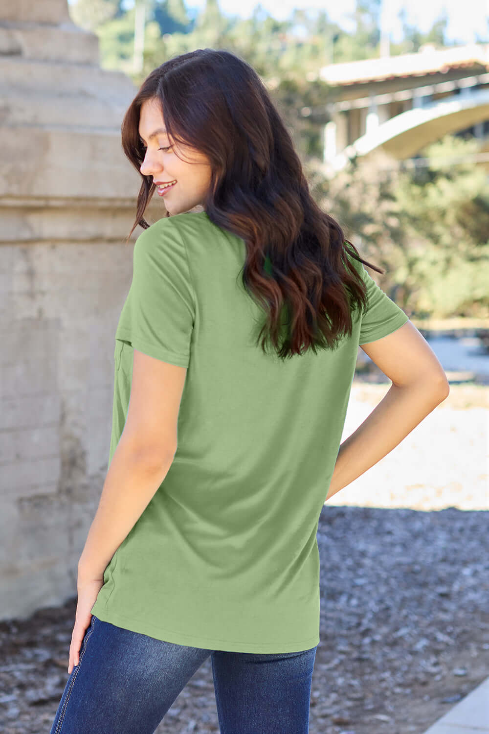 Woman wearing Basic Bae Bamboo V-Neck Short Sleeve T-Shirt in green, standing outdoors with her back turned