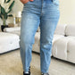 Person wearing High Waist Distressed Straight Jeans by Judy Blue Jeans, styled with black sneakers, standing in a modern living room.