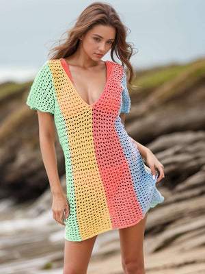 Woman wearing a colorful openwork V-neck short sleeve cover-up, standing on a beach.