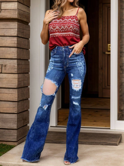 Model wearing raw hem distressed bootcut jeans paired with a red tank top, showcasing trendy and edgy fashion style