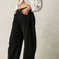 Woman wearing black wide leg jeans with pockets, paired with a white cropped blouse featuring eyelet details.