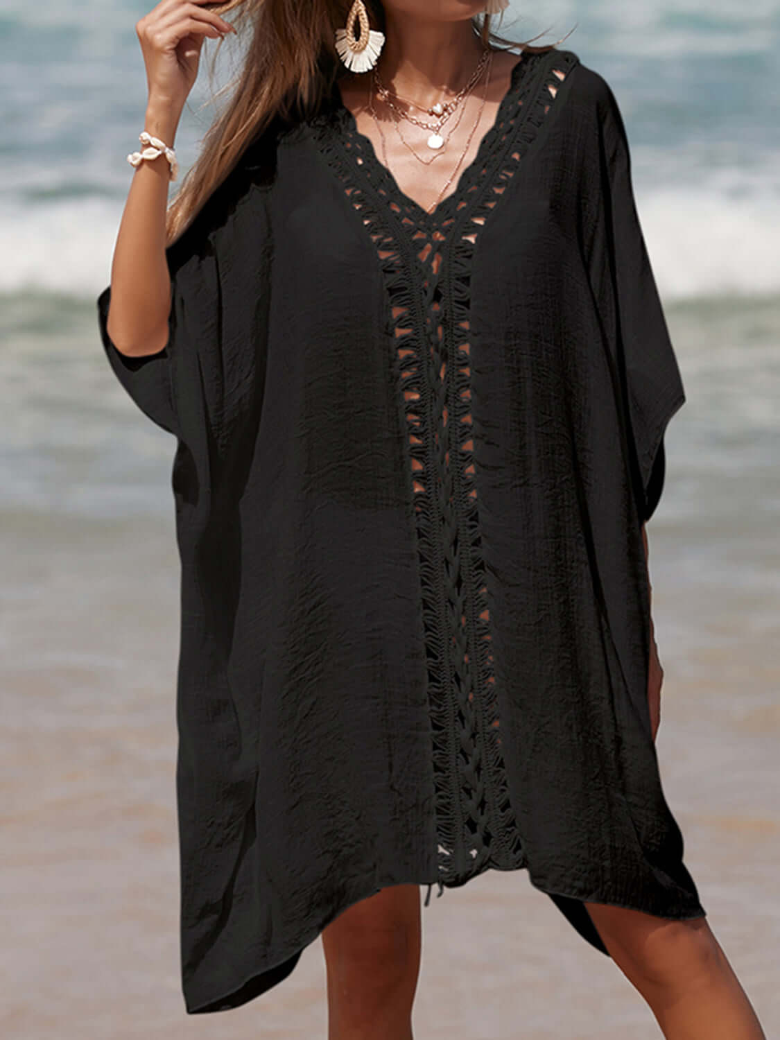 Woman wearing black cutout V-neck three-quarter sleeve cover up on a beach