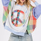 Model wearing SAGE + FIG Contrast Peace Patch Sweatshirt with colorful sleeves and peace logo.