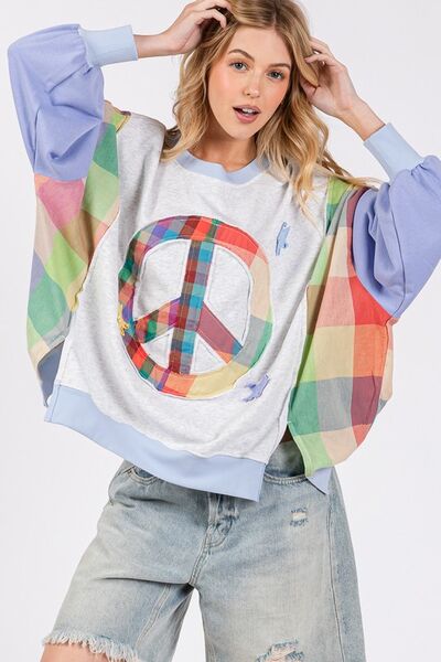 Model wearing SAGE + FIG Contrast Peace Patch Sweatshirt with colorful sleeves and peace logo.