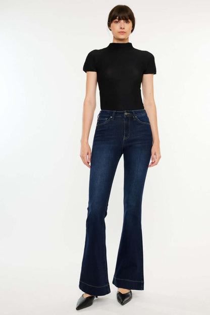 Woman wearing Kancan High Rise Slim Flare Jeans in dark wash, paired with a black top and heels, showcasing a chic, polished look.