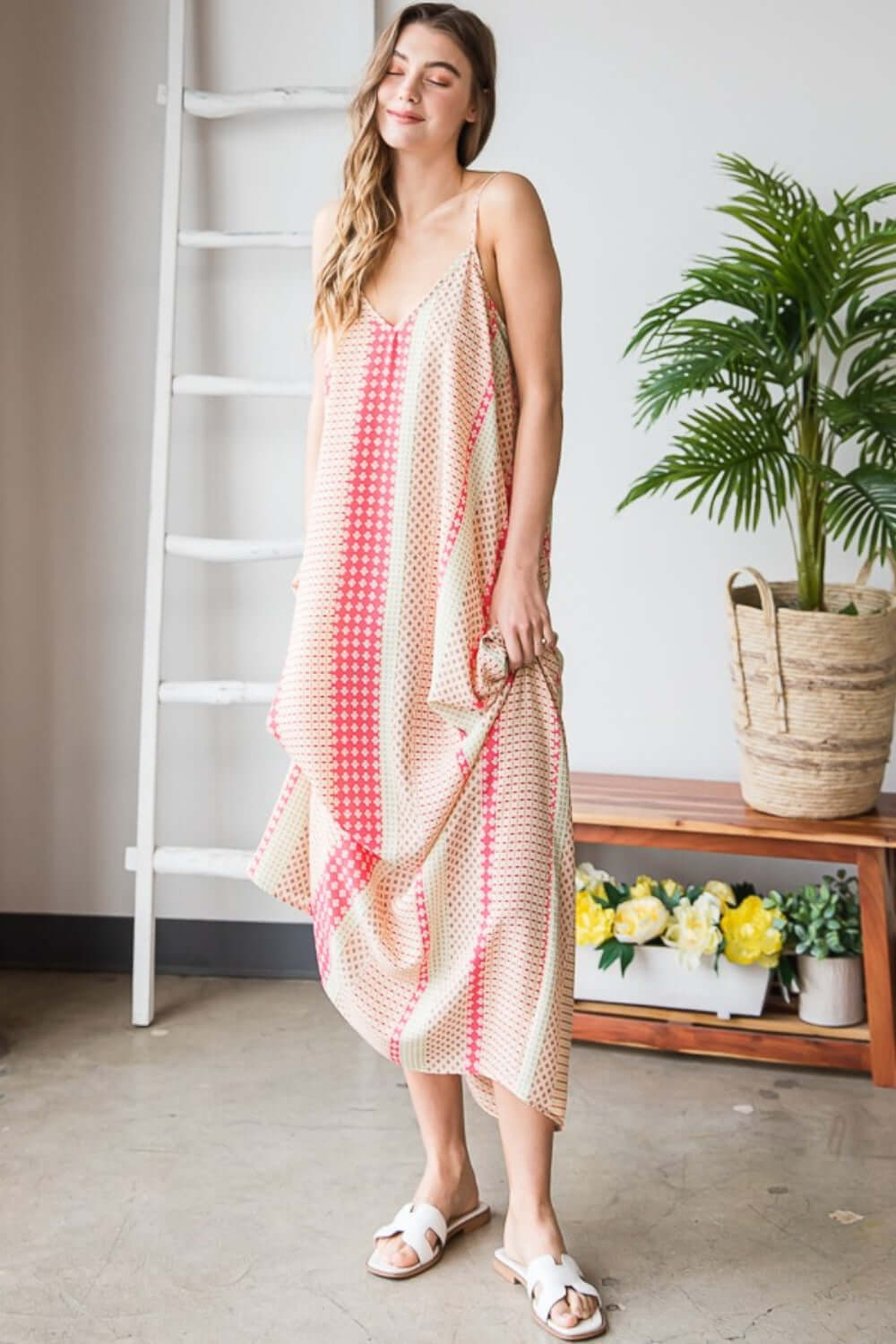 Woman wearing Printed Maxi Cami Dress with Pockets in vibrant pattern and standing in a stylish room