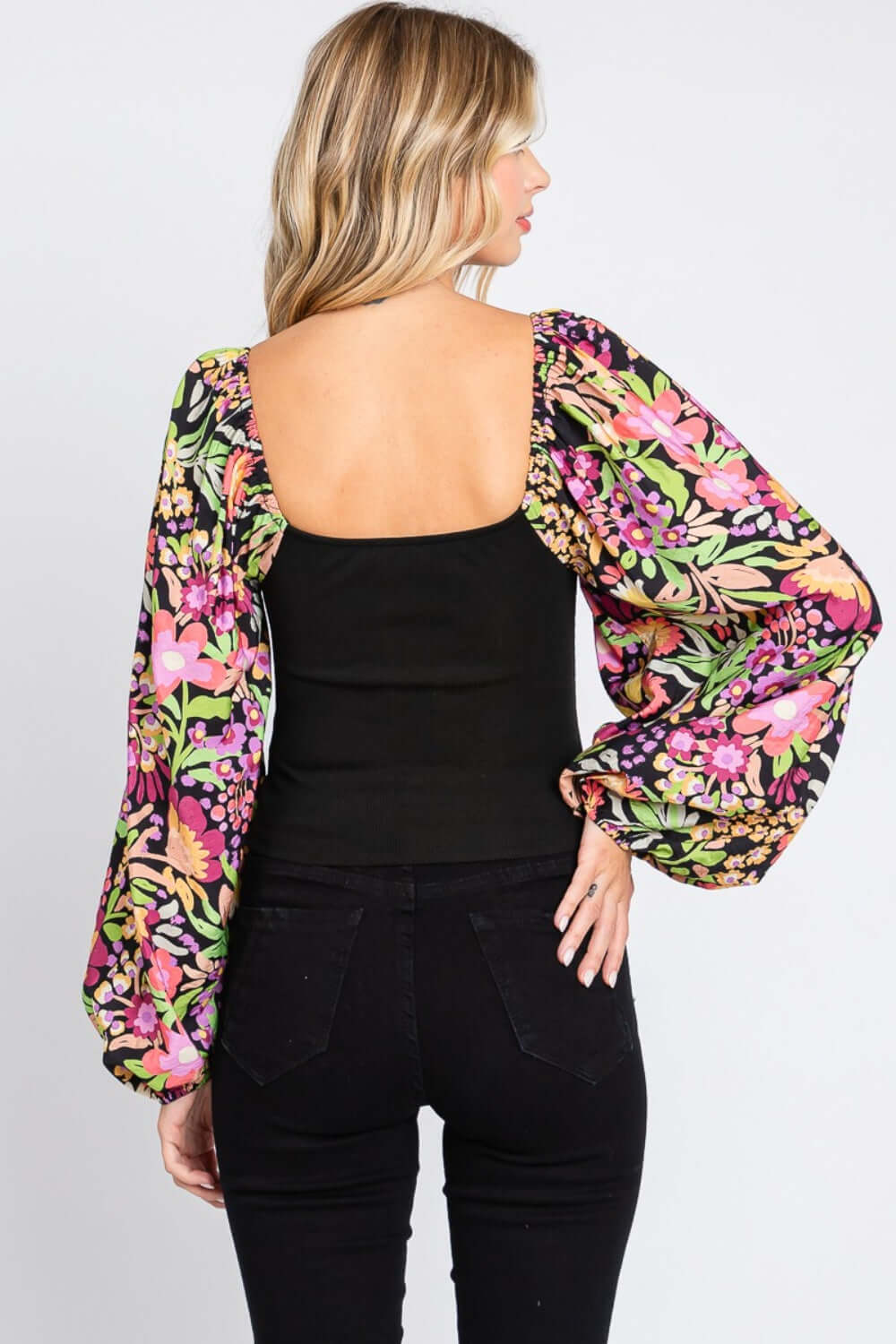 Woman wearing a chic Floral Balloon Sleeve Blouse with elegant floral print and dramatic balloon sleeves, showing back view.