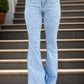 Person wearing trendy raw hem bootcut jeans with button and pocket details, standing on stairs