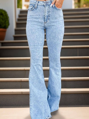 Person wearing trendy raw hem bootcut jeans with button and pocket details, standing on stairs