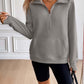 Woman wearing Ivy Lane Half Zip Raglan Sleeve Sweatshirt in gray with pocket detail and black shorts in stylish indoor setting.