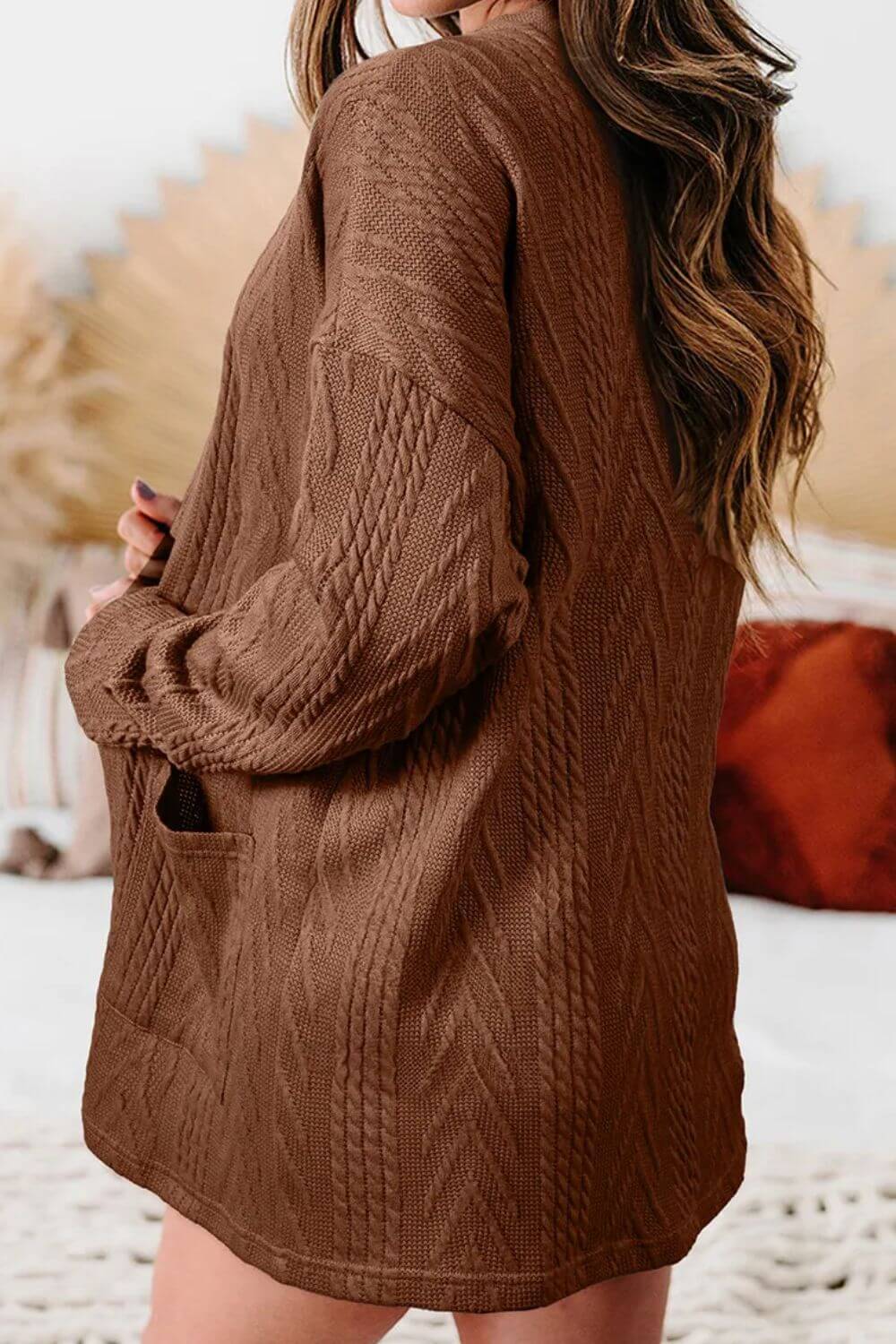 Woman wearing a textured open front cover up with pockets in brown, slightly stretchy fabric.