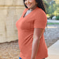 Woman wearing Basic Bae Bamboo V-Neck Short Sleeve T-Shirt in orange, smiling outdoors while showcasing the comfy and stylish tee.