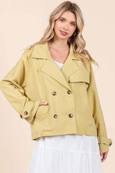 Woman wearing a stylish yellow double-breasted trench coat jacket over a white dress, perfect for transitional weather.