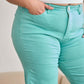 Woman wearing high waist mint green jeans with a white top showing tummy control feature