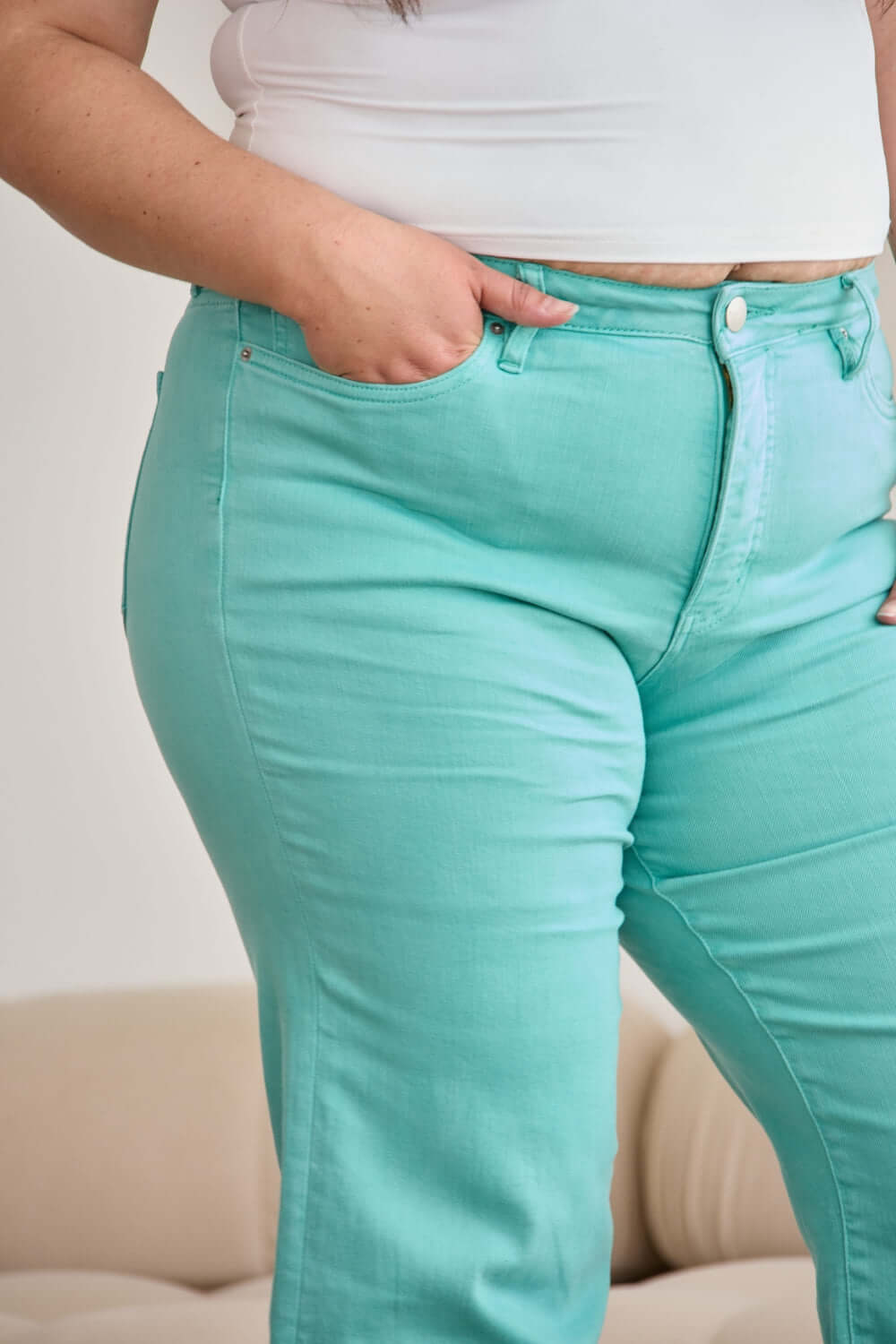 Woman wearing high waist mint green jeans with a white top showing tummy control feature