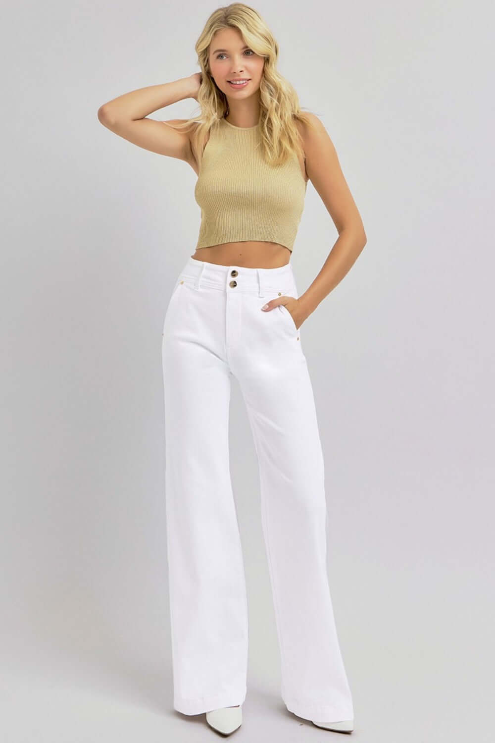 Woman wearing RISEN Full Size Tummy Control Double Button Wide Leg Jeans in white with a beige top, striking a stylish pose.