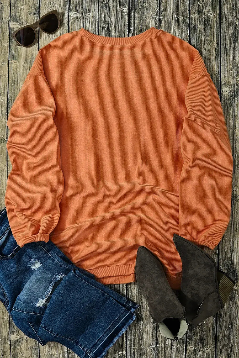 Bella Road Hey Boo Graphic Round Neck Long Sleeve Sweatshirt in orange laid out with jeans, boots, and sunglasses on a wooden surface.