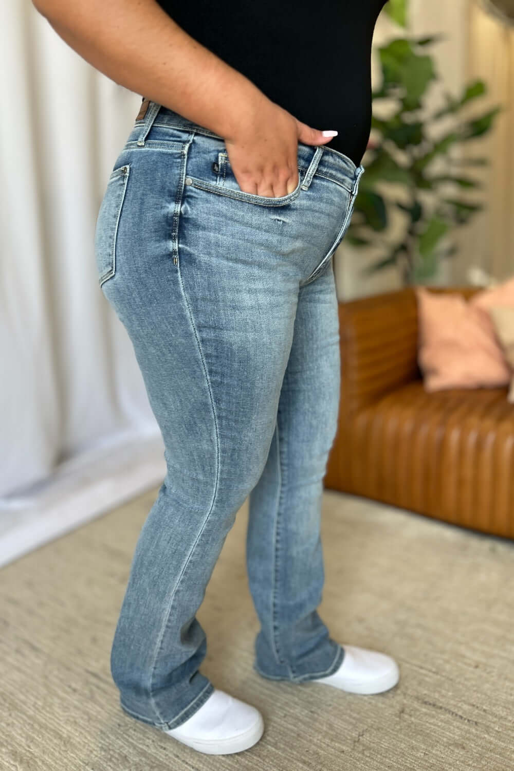 Woman wearing Judy Blue medium rise bootcut jeans, showcasing the flattering fit and high-quality denim for versatile style.