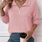 Woman wearing striped pink half zip long sleeve t-shirt with jeans, holding a coffee cup.