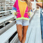 Woman wearing Bella Road Color Block Round Neck Long Sleeve Top with denim shorts and white sneakers on bleachers.