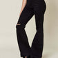 Woman wearing high waist distressed black flare jeans from Judy Blue, paired with a white top and black sandals.