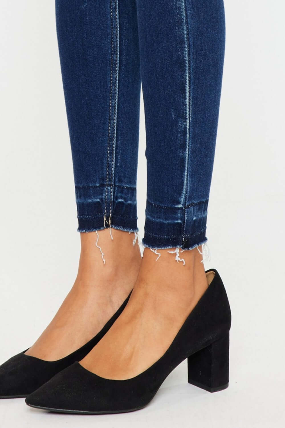 Stylish high-rise ankle skinny jeans with release hem detail, paired with chic black heels for a trendy look.