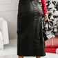 Woman in Bella Road Slit PU Leather Midi Skirt with bold slit design, styled with red top and black heels, holding a black handbag.