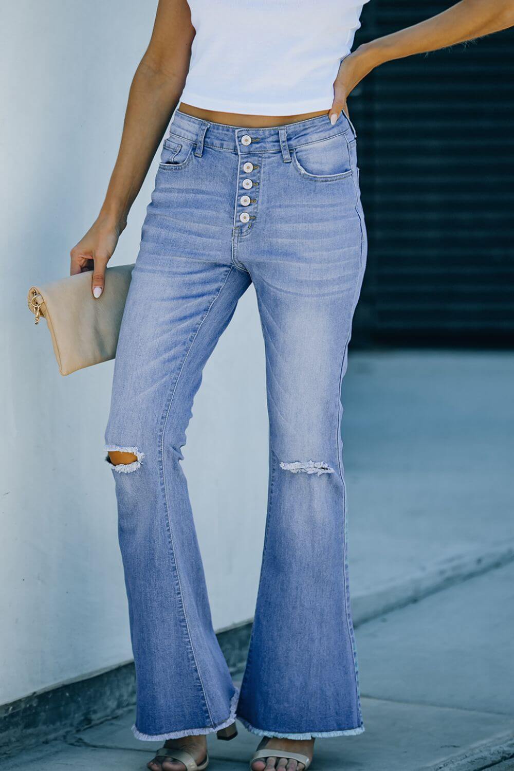 Woman wearing Bella Road Button-Fly Distressed Raw Hem Flare Jeans with a white top, showcasing buttoned and distressed details.