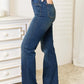 Model wearing Judy Blue Elastic Waistband Slim Bootcut Jeans, showcasing side view fit and style in a bedroom setting.