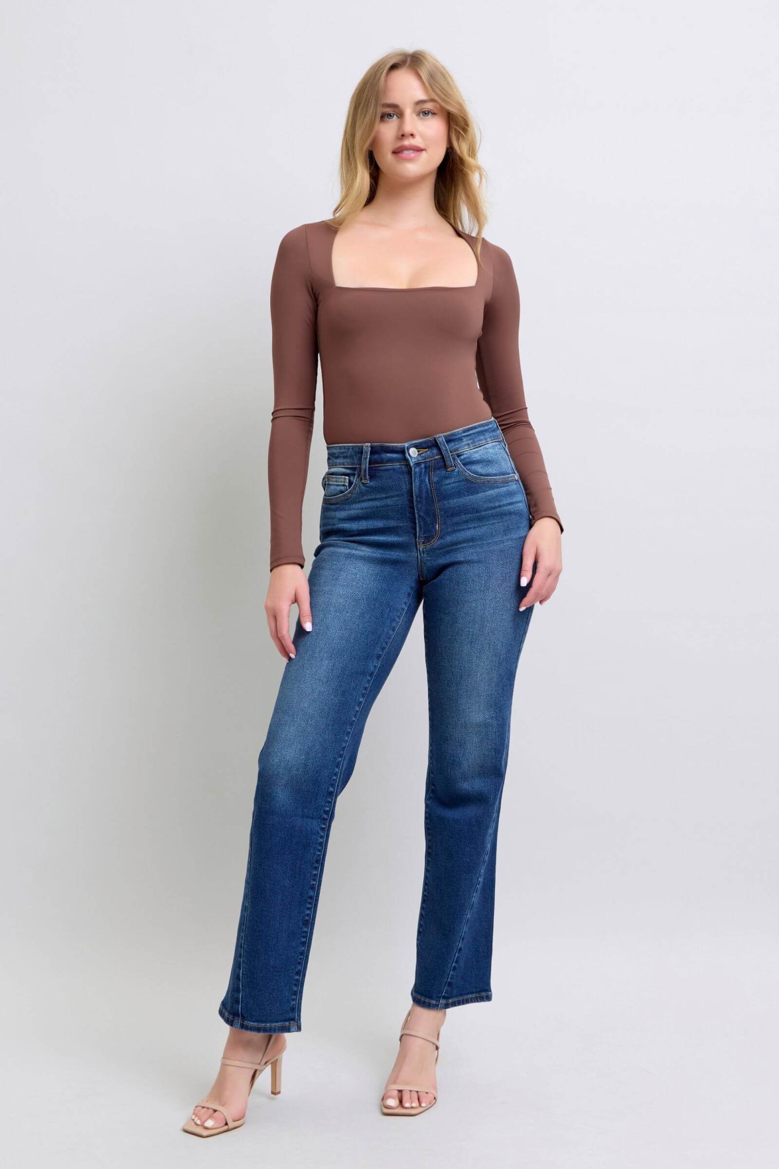 Model showcasing Judy Blue side seam detail straight jeans with pockets, styled with a fitted brown top and strappy heels.