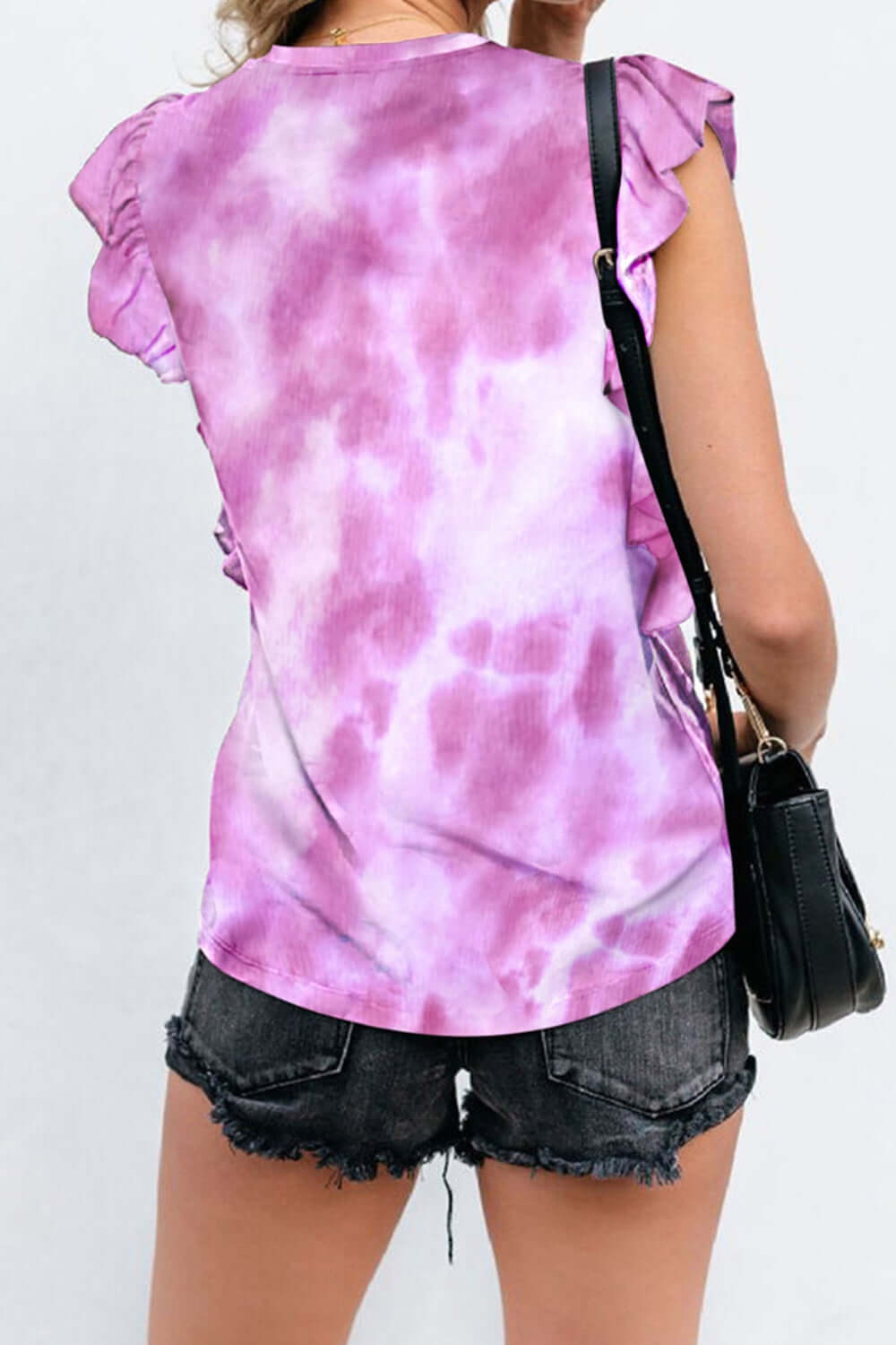 Woman wearing Bella Road Ruffled Printed T-Shirt with cap sleeves and tie-dye pattern, styled with black denim shorts.