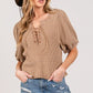 SAGE+FIG lace-up waffle knit crop top styled with denim shorts and a chic hat for a trendy casual look.