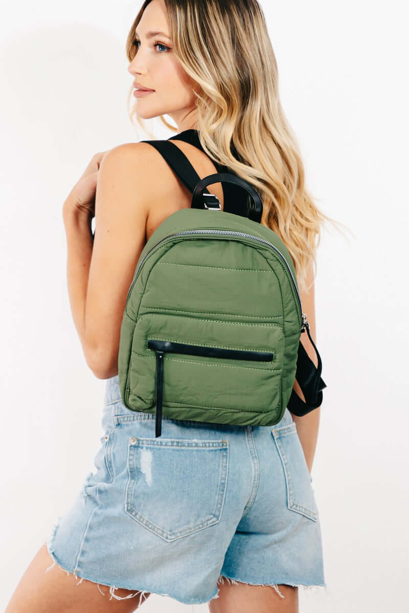 Stylish woman wearing a green adjustable strap nylon backpack, showcasing its lightweight and durable design.