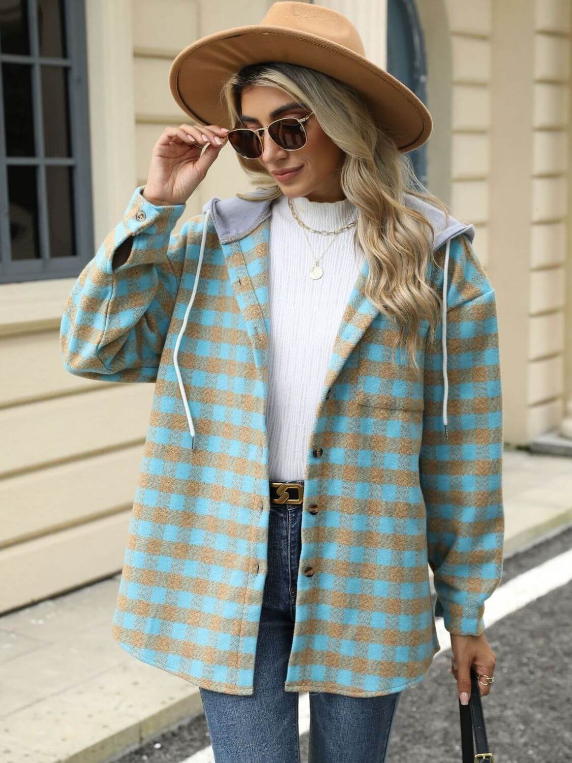 Woman wearing Bella Road Drawstring Plaid Long Sleeve Hooded Jacket with white sweater and jeans, accessorized with sunglasses and hat