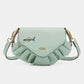 Light green Nicole Lee USA crossbody bag with pleated detailing and "Stay Magical" graphic on the flap.