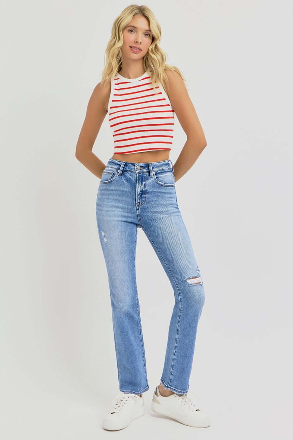 Woman wearing RISEN high-rise ankle straight jeans with distressed details and a striped top.