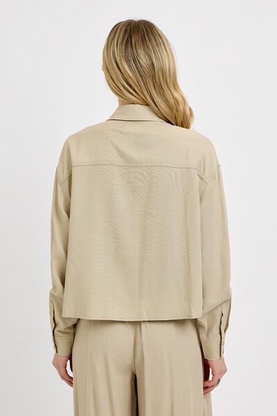 Back view of a woman wearing a beige RISEN Button Down Long Sleeve Shirt, showcasing the classic style.