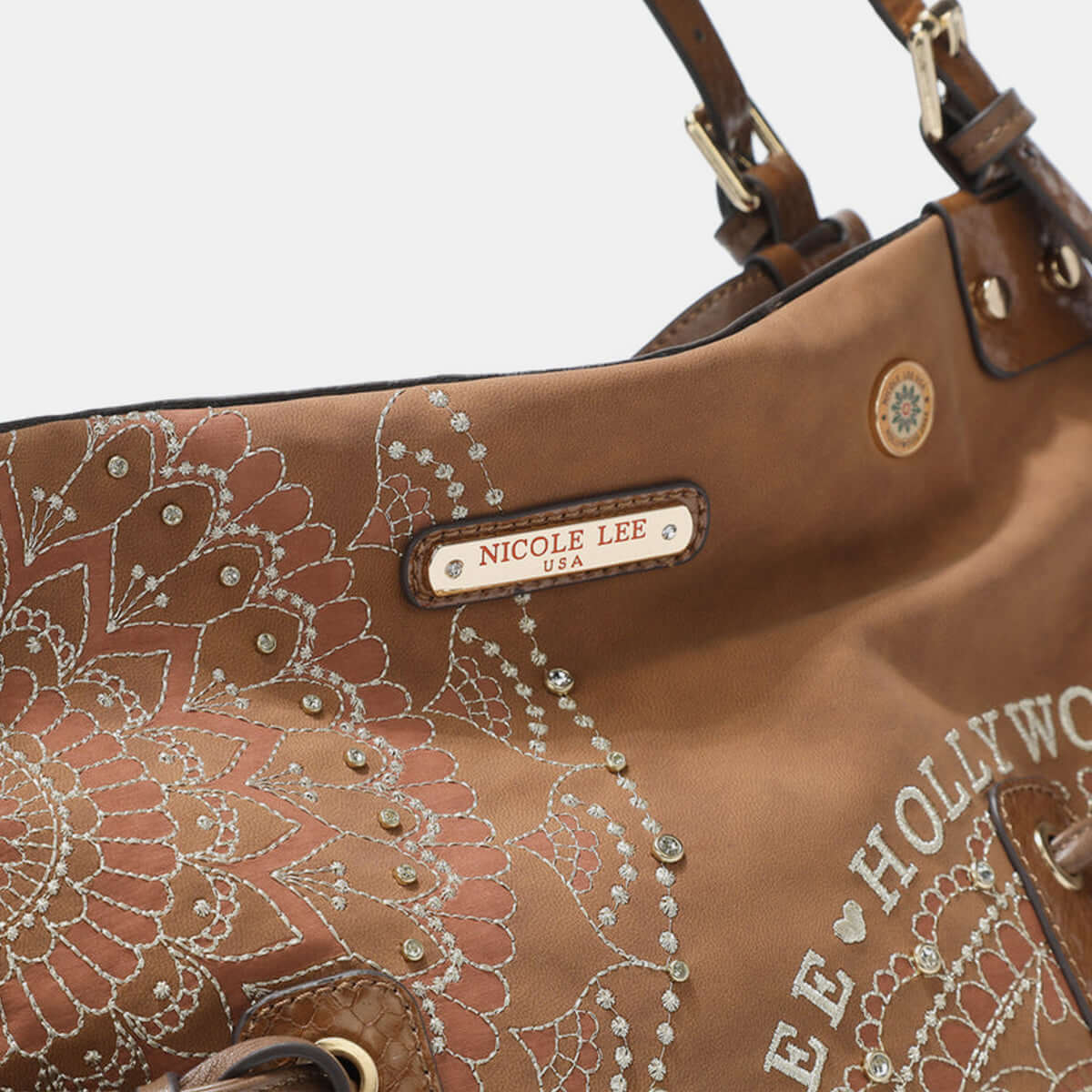 Close-up of Nicole Lee USA hobo bag showing vegan leather with embroidered design and Nicole Lee nameplate.