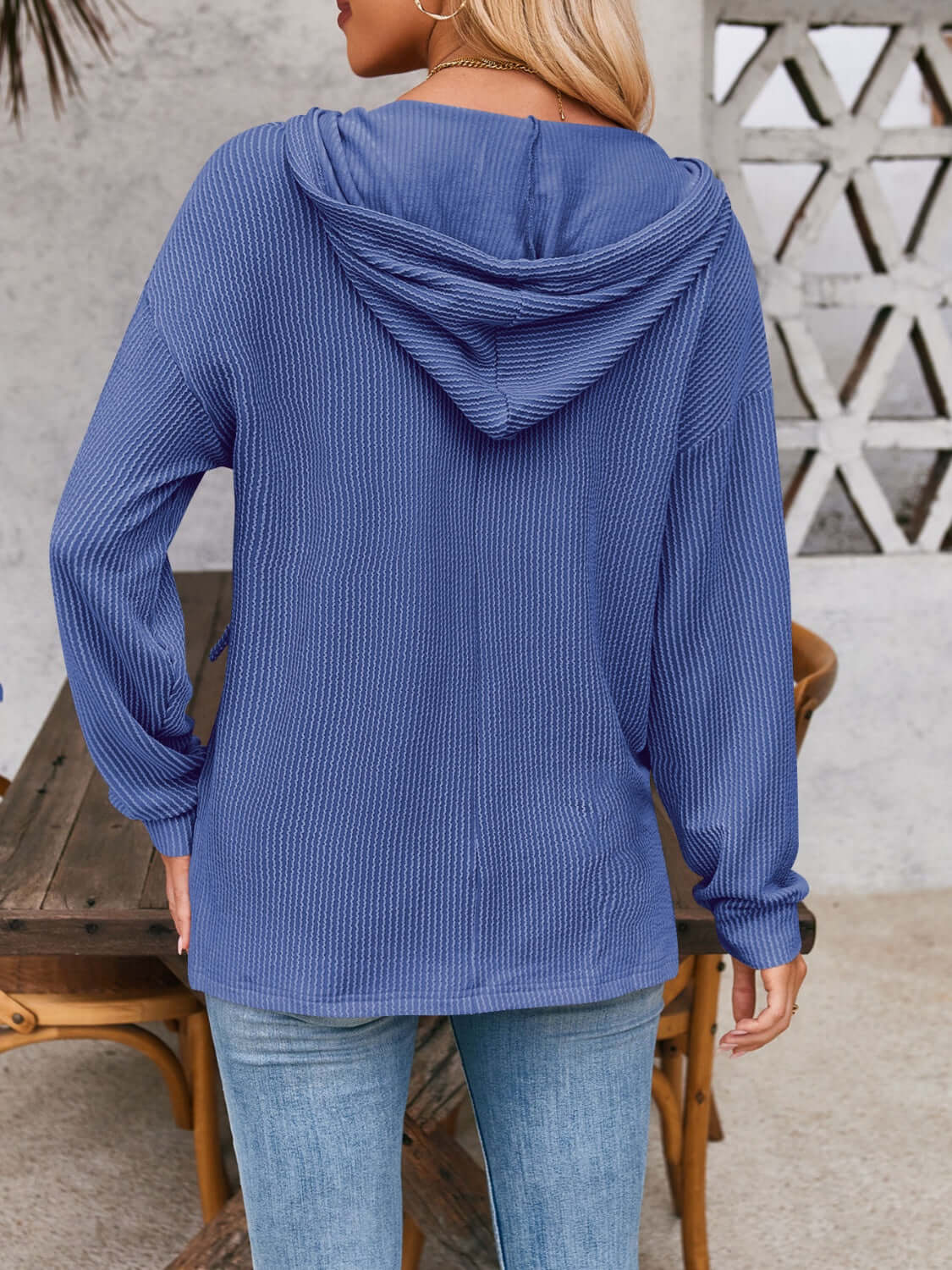 Woman wearing blue drawstring dropped shoulder long sleeve hoodie from the back.