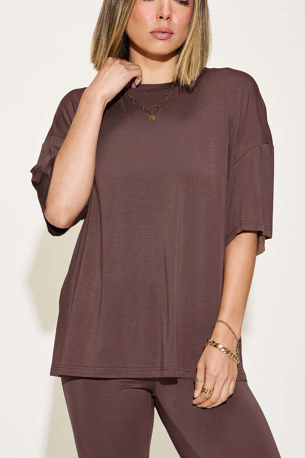 Woman wearing bamboo drop shoulder t-shirt and flare pants set in brown. Stylish two-piece outfit with stretchy, comfortable fit.