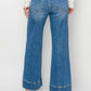 Woman wearing High Rise Wide Leg Jeans by Risen Jeans with a chic retro-inspired look and comfortable wide leg design.