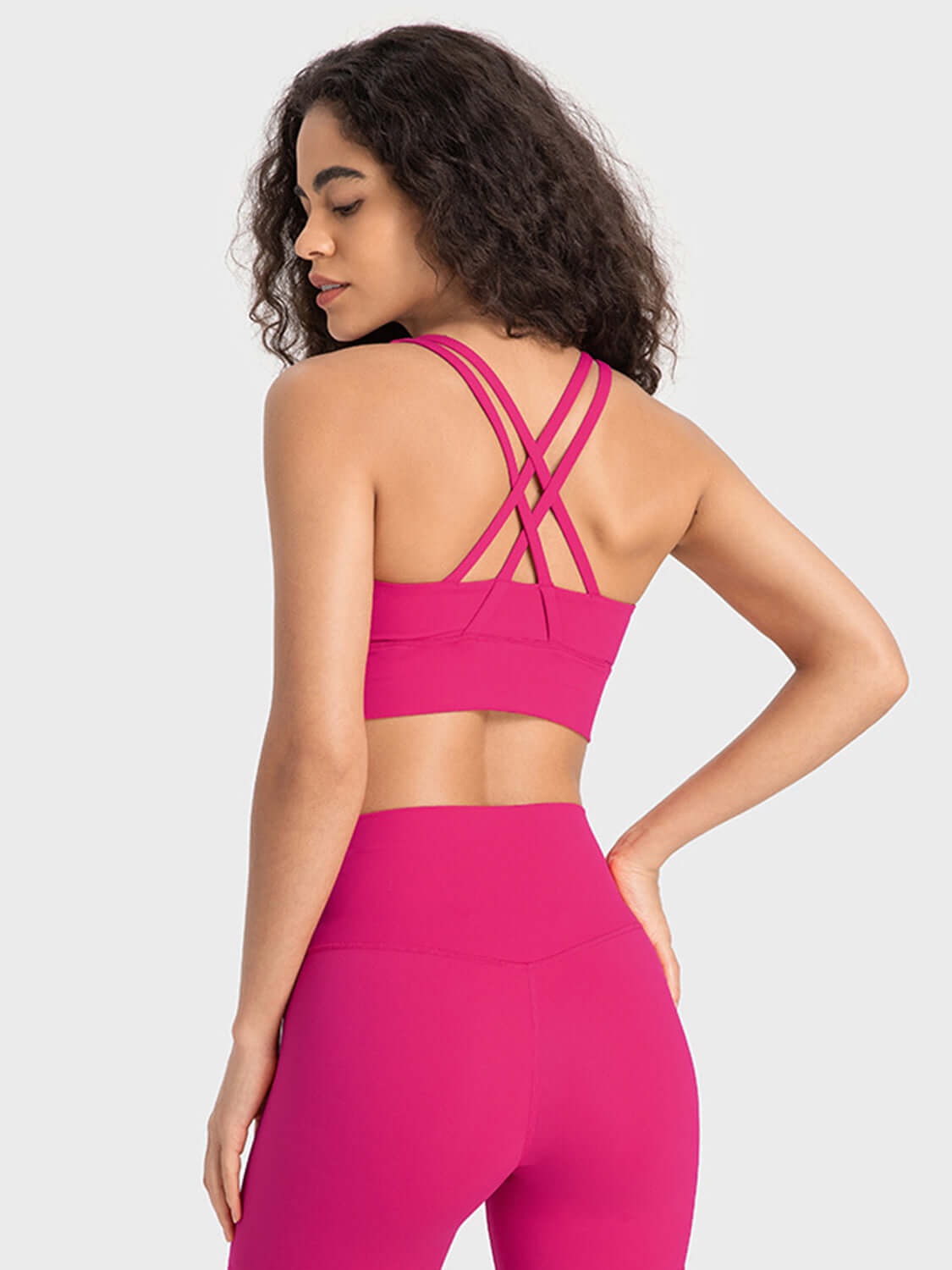 Model showcasing the Millennia Crisscross Scoop Neck Active Tank in vibrant pink, highlighting stylish back design.